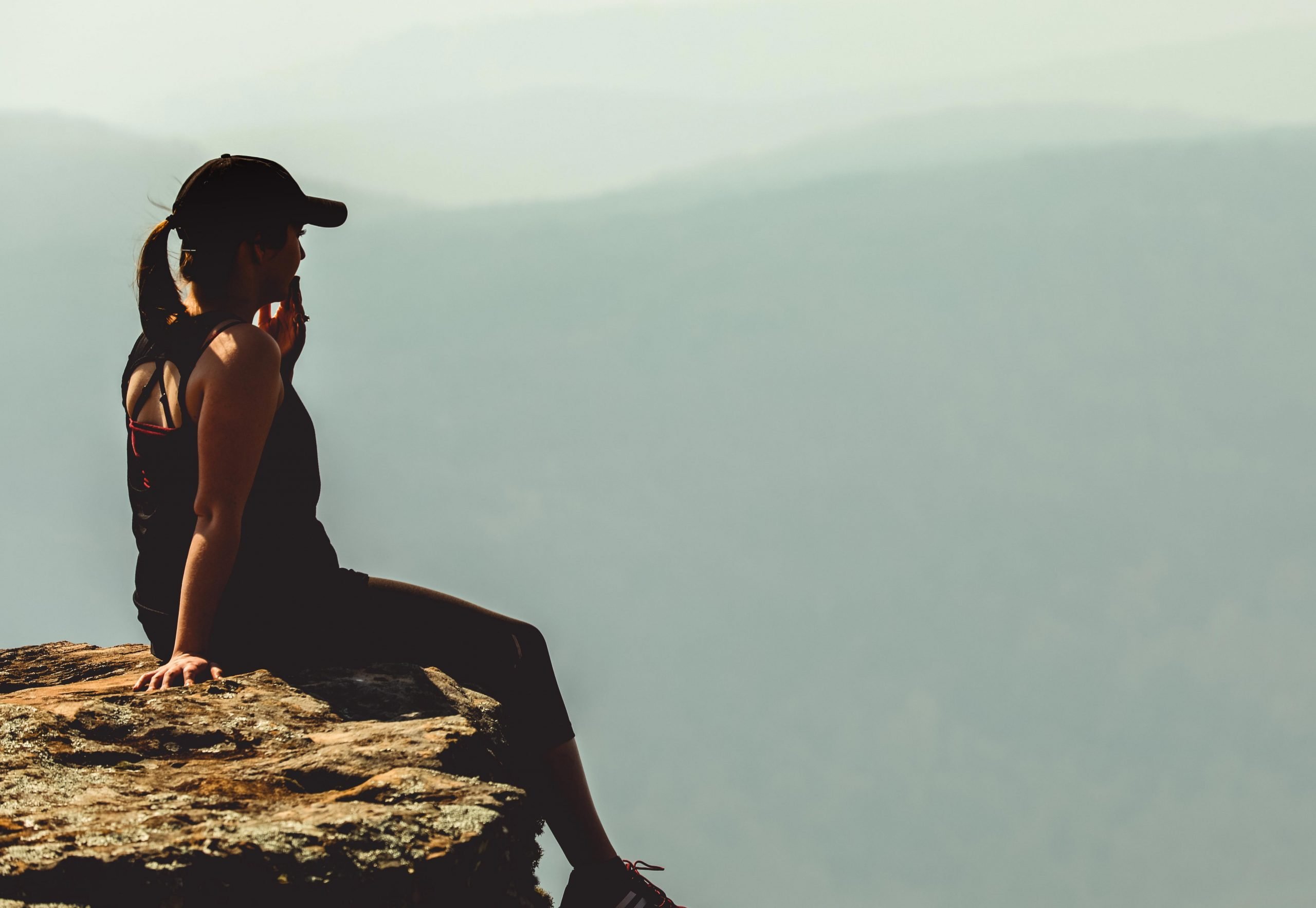 woman sitting on cliff