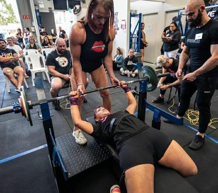 Ingrid handing barbell out to coaching client Simone in black shorts and top